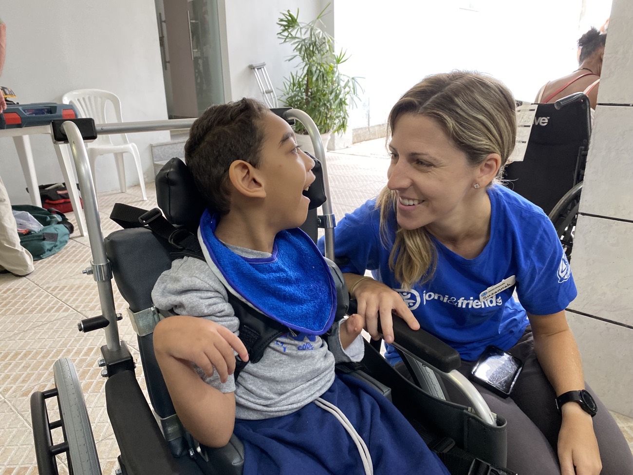 Voluntária conversando com menino em cadeira de rodas